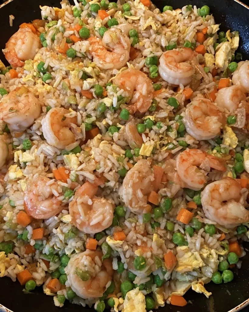 finished shrimp fried rice meme in a wok with scrambled egg and green peas
