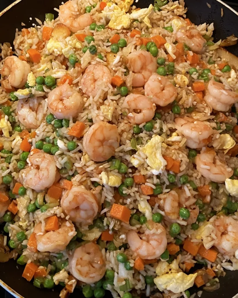 shrimp fried rice sizzling in a skillet with bright vegetables and golden shrimp