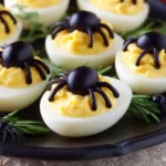 Spider deviled eggs made with black olive spiders on a tray for Halloween